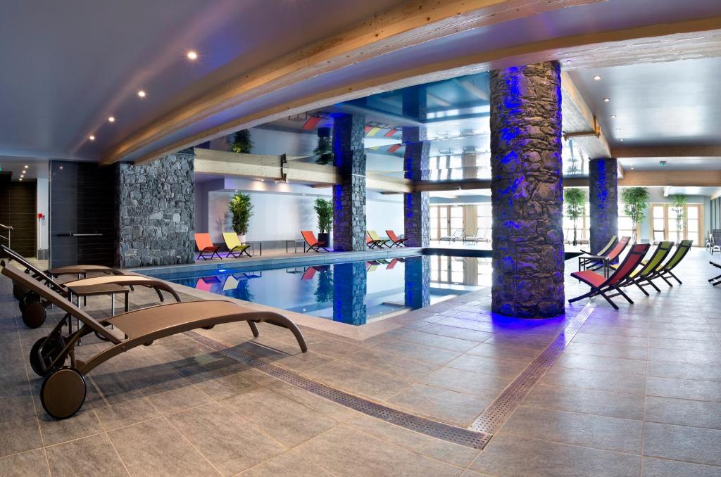 a swimming pool in a building with chairs at CGH Résidences & Spas Le Cristal de l'Alpe in L'Alpe-d'Huez
