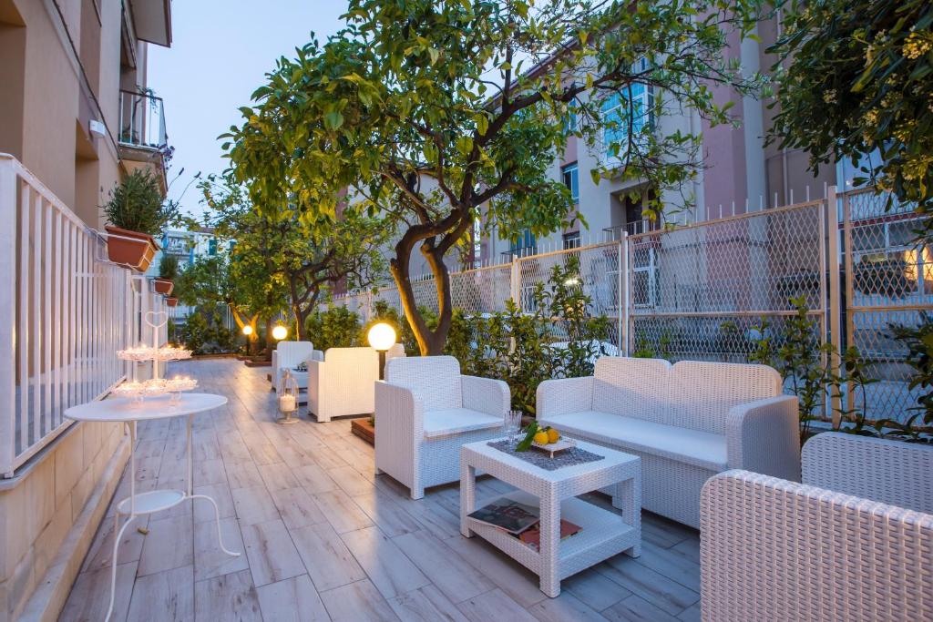 patio z białymi krzesłami i stołami oraz drzewem w obiekcie Dolci Agrumi w Syrakuzach