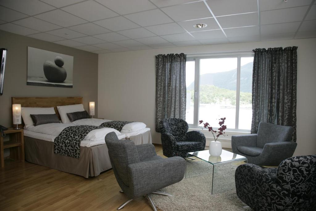 a bedroom with a bed and chairs and a window at Brattvåg Fjordhotell in Brattvåg