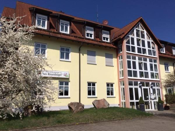 ein großes gelbes Gebäude mit braunem Dach in der Unterkunft Hotel & Restaurant am Rosenhügel in Jüchsen