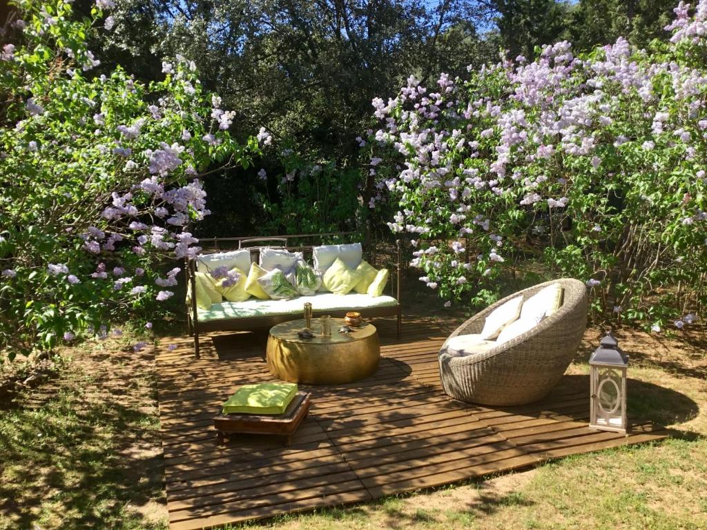 une terrasse en bois avec un canapé et une chaise dans un jardin dans l'établissement Longo Maï, à Sillans-la-Cascade