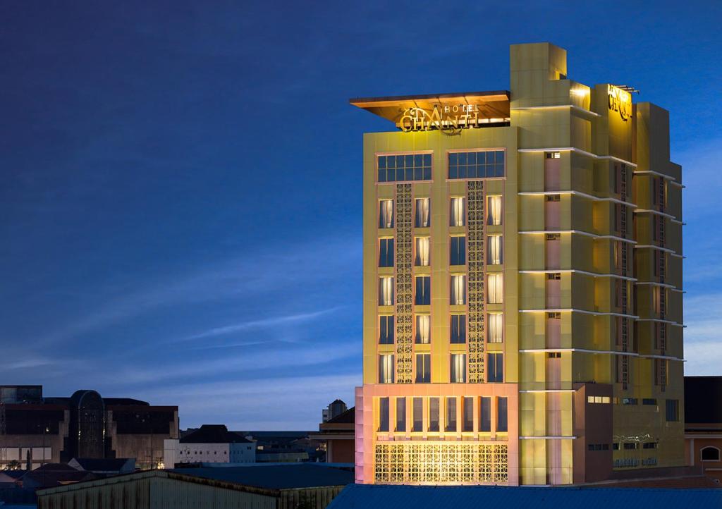 a tall hotel building with a lit up sign on it at Hotel Chanti Managed by TENTREM Hotel Management Indonesia in Semarang