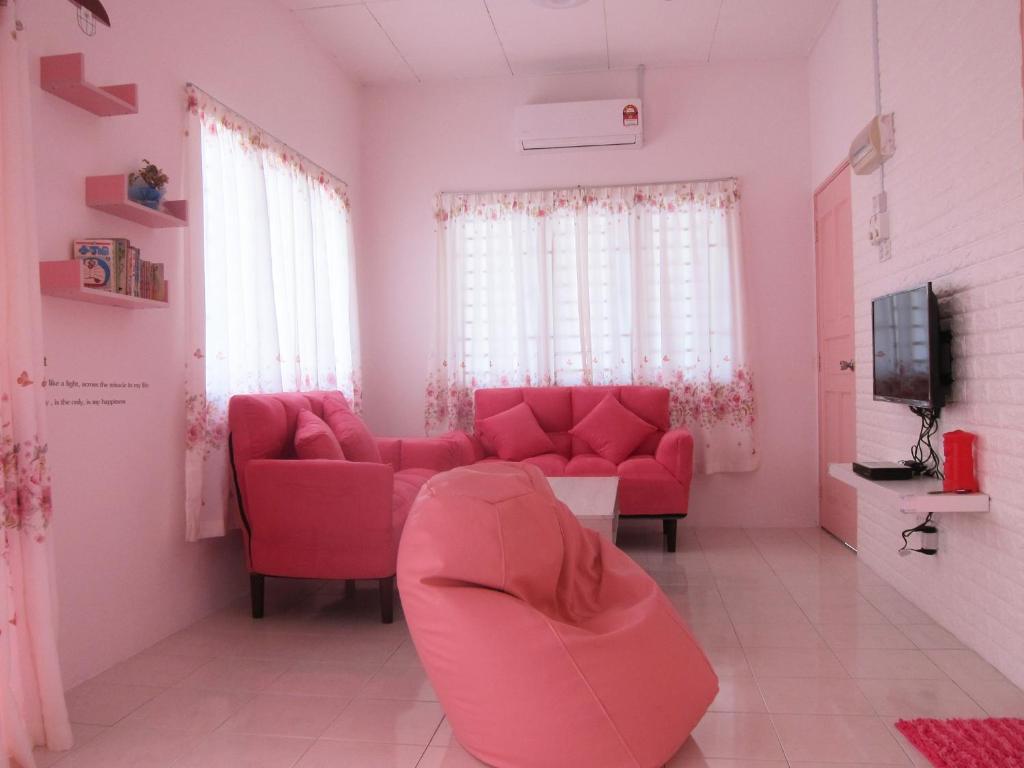 ein rosafarbenes Wohnzimmer mit einem roten Sofa und einem TV in der Unterkunft MILU Homestay - Kuala Selangor in Kuala Selangor