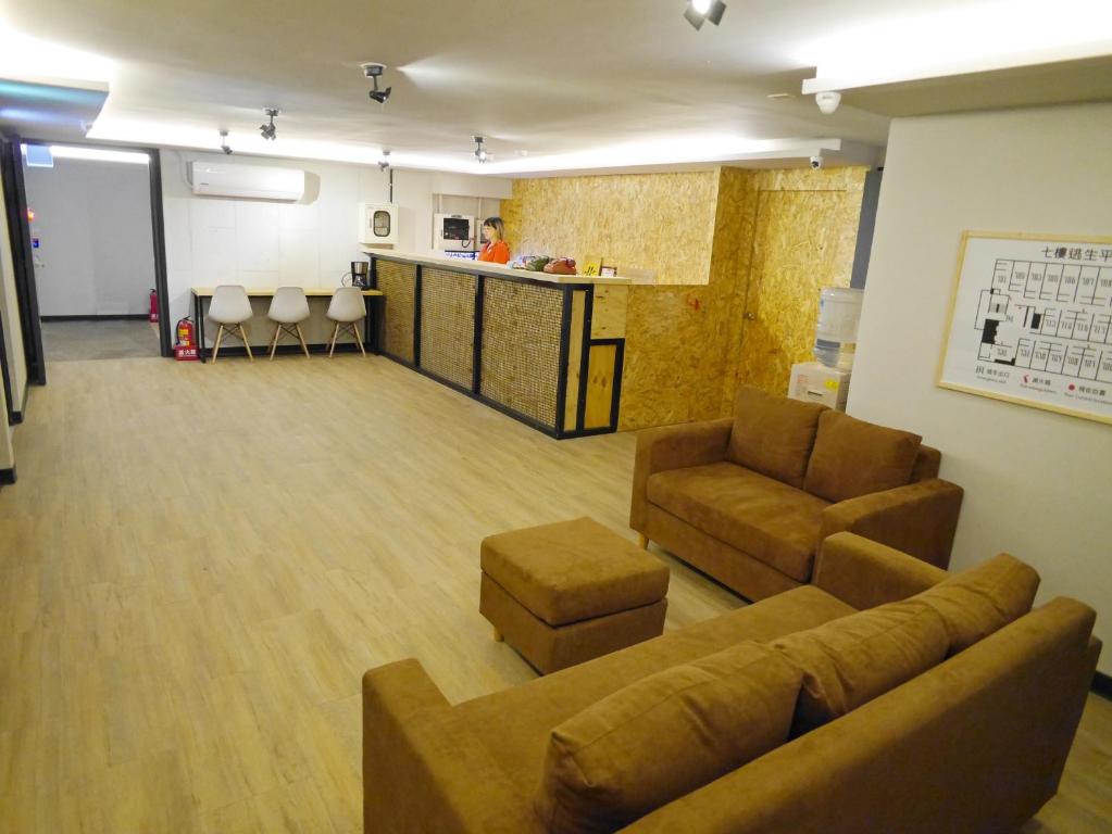 a living room with a couch and chairs and a counter at Good Night Hotel in Yangmei