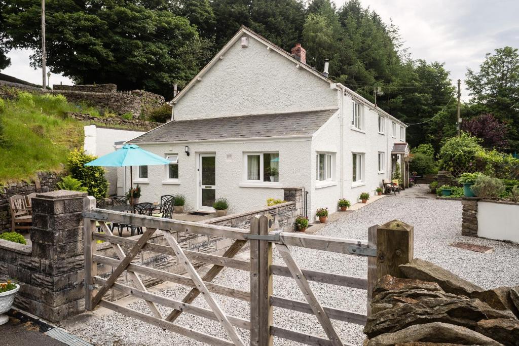 a white house with a fence and an umbrella at 1 Tan Yr Eglwys Barn Cottage in Pontardawe