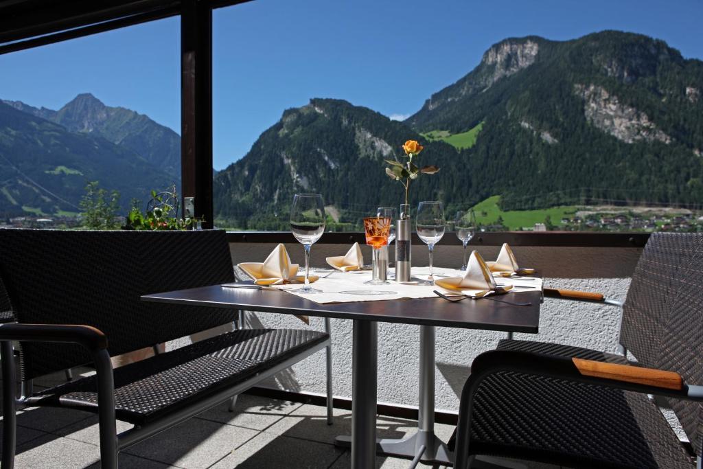 a table with wine glasses and a view of mountains at Hotel Eckartauerhof in Mayrhofen