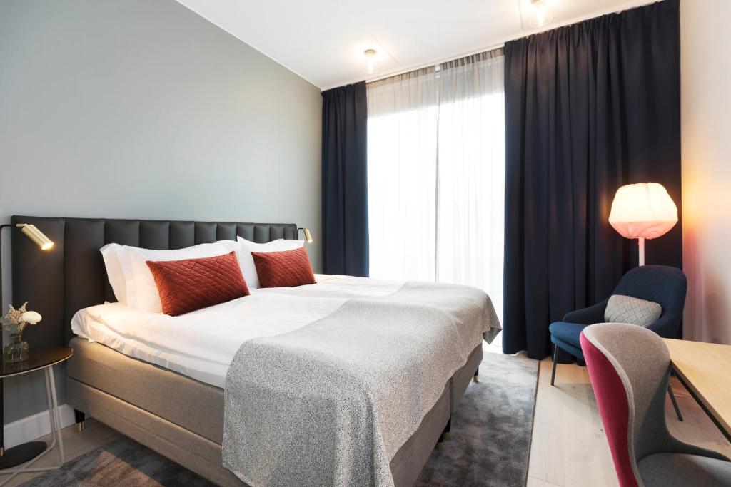 ウプサラにあるエリート ホテル アカデミアの大きなベッドと椅子が備わるホテルルームです。