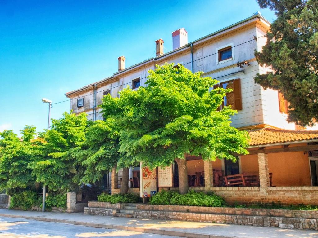 uma casa velha com árvores em frente em Apartments Fazanka 849 em Fažana