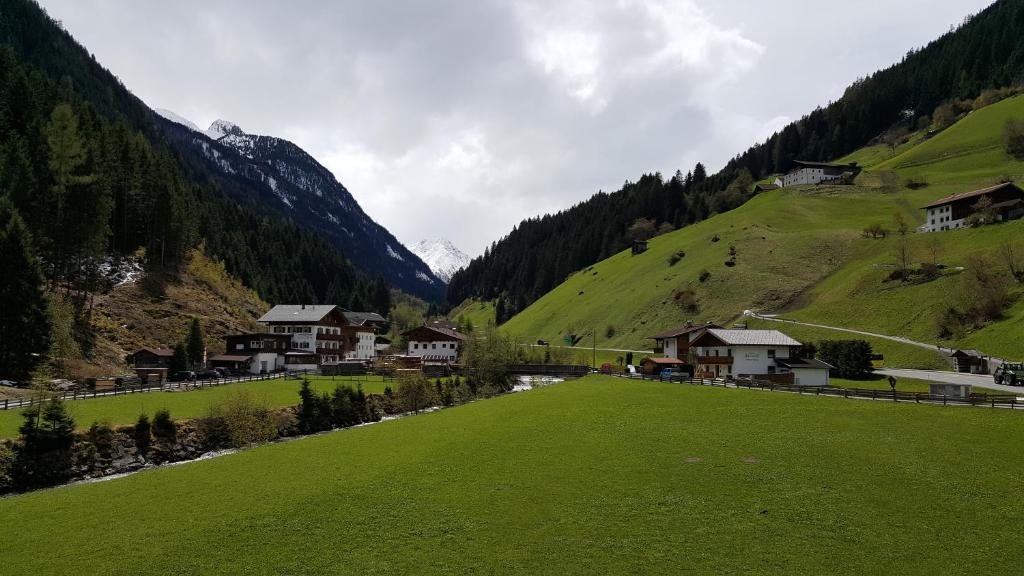 een groen veld met huizen in de bergen bij Gasperlerhof in Neustift im Stubaital