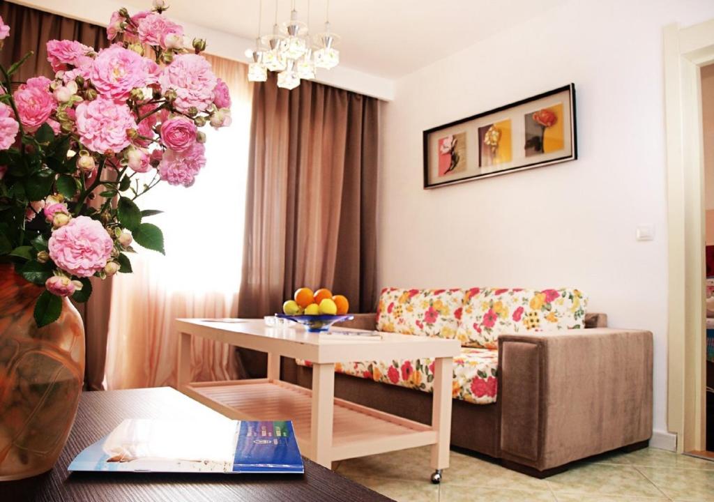 a living room with a table and pink flowers at Hotel Majestic Mamaia in Mamaia