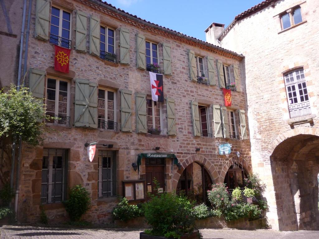 ein großes Backsteingebäude mit Flaggen darauf in der Unterkunft Chambres d'hôtes l'Escuelle des Chevaliers in Cordes-sur-Ciel