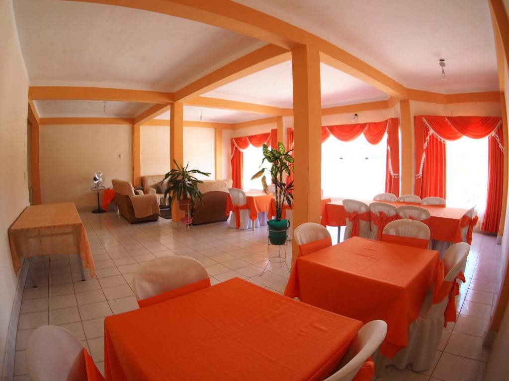 jadalnia z pomarańczowymi stołami i krzesłami w obiekcie Hostal Butch Cassidy w mieście Tupiza