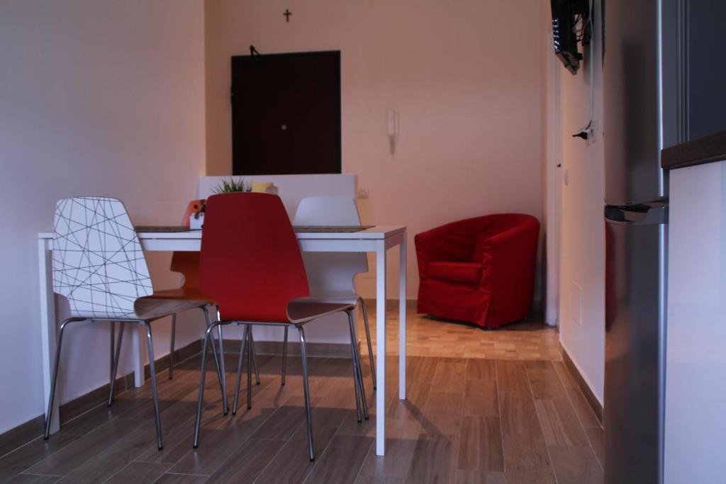ミラノにあるスティーブンソン　アパートメントのテーブルと椅子、赤い椅子が備わる客室です。
