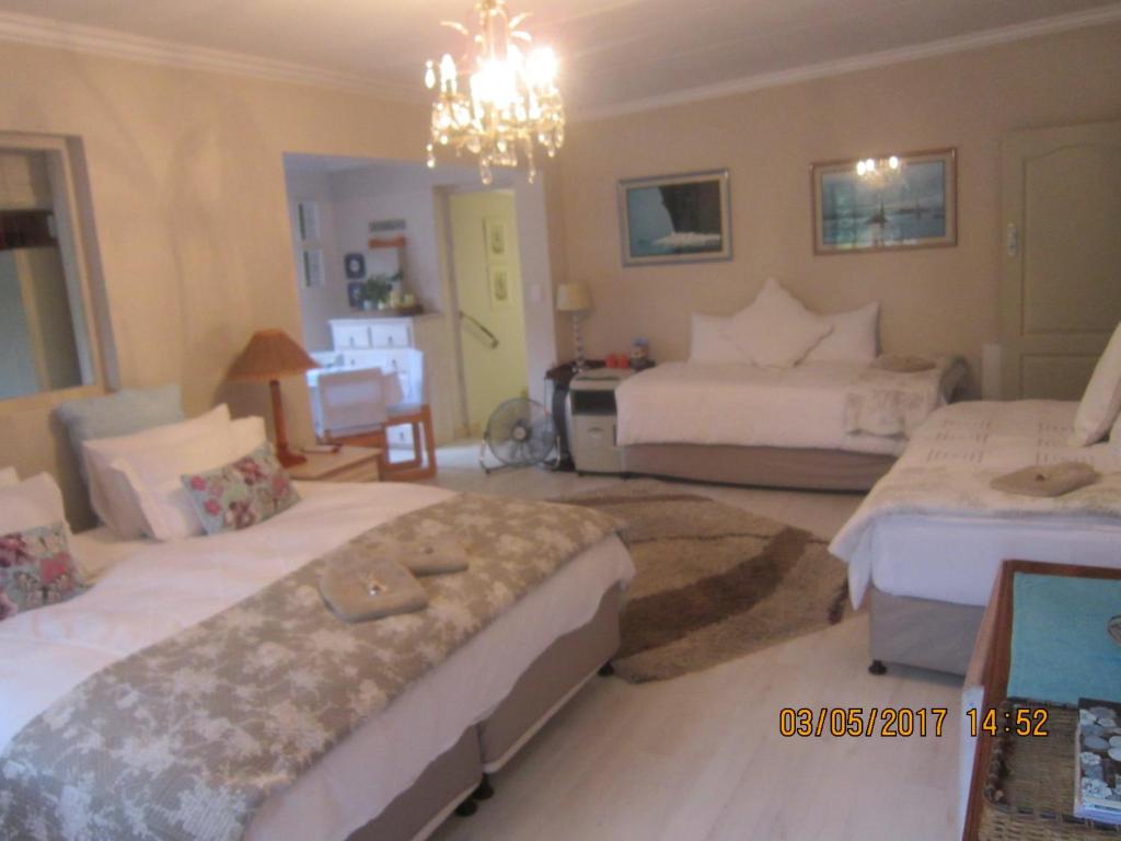 a bedroom with two beds and a chandelier at Twilight Cottage in Plettenberg Bay