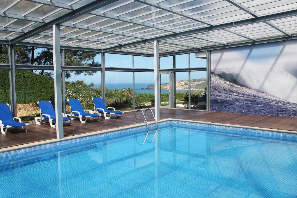 een zwembad met stoelen en uitzicht op de oceaan bij Hotel Miramar Sul in Nazaré