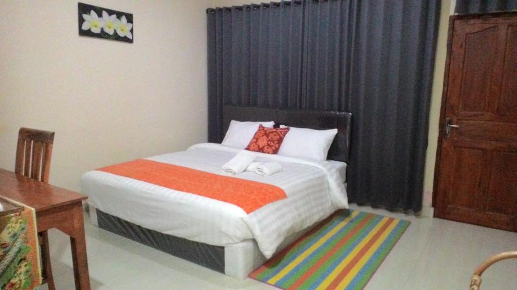 a bedroom with a large bed with an orange blanket at Griya Bun Sari in Sukawati