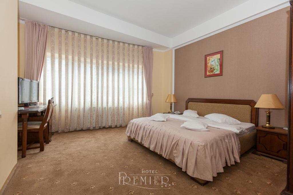 クルジュ・ナポカにあるHotel Premierのベッド、デスク、窓が備わるホテルルームです。