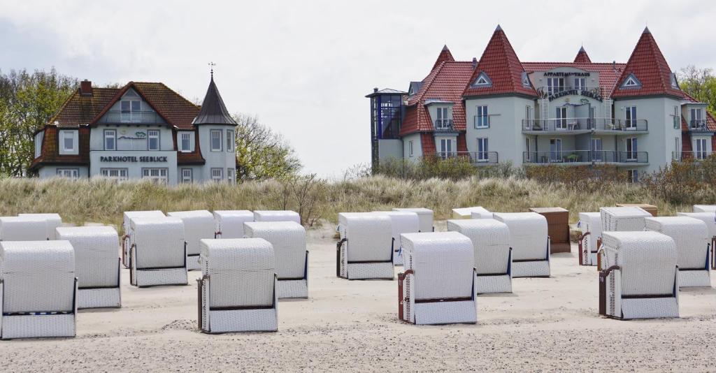 um monte de cadeiras sentadas na areia em frente às casas em Parkhotel Seeblick em Warnemünde