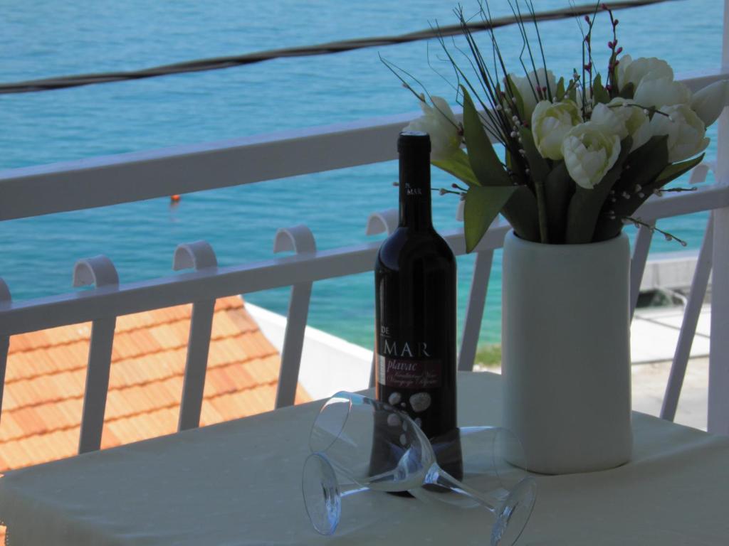 a bottle of wine and glasses on a table with flowers at Apartment Adria in Trogir