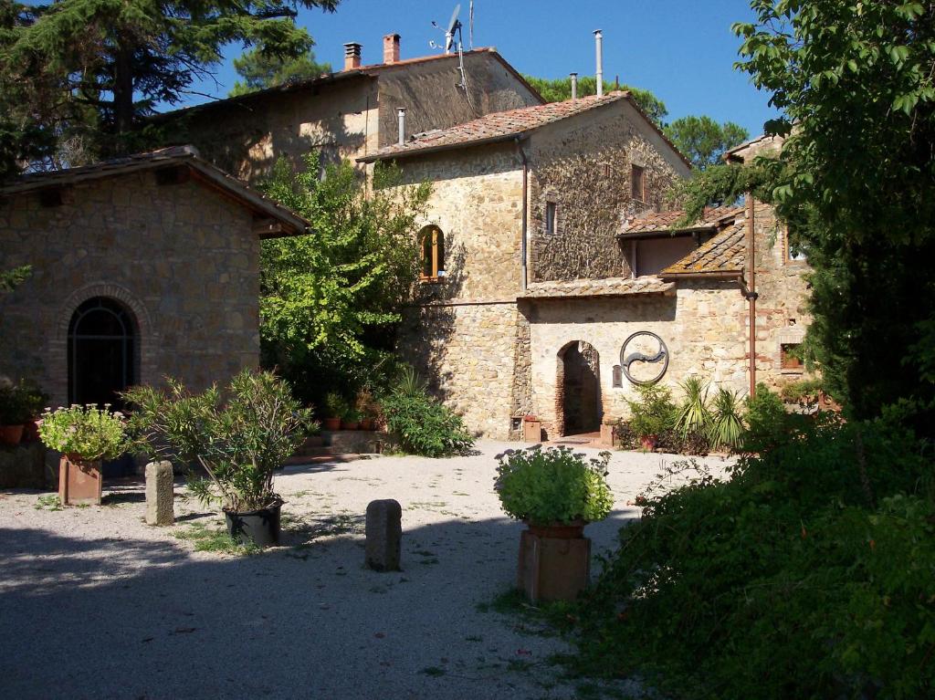a large stone building with trees and plants in front of it at Casa Vacanze Good Buy in San Gimignano