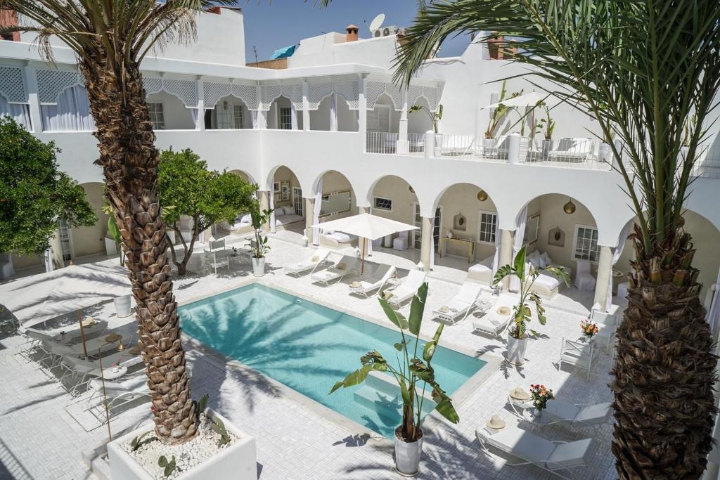 una imagen de un hotel con palmeras y piscina en Riad Palais Blanc & Spa, en Marrakech