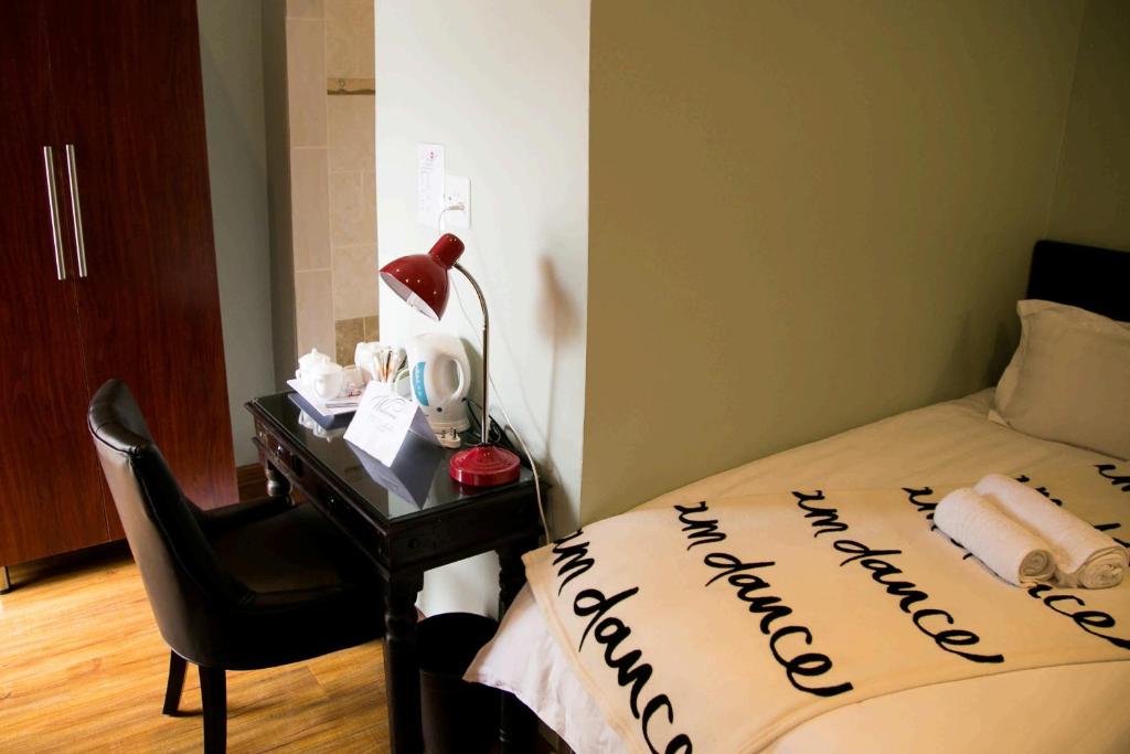 1 Schlafzimmer mit einem Bett und einem Schreibtisch mit einem Bett von sidx sidx sidx in der Unterkunft Guesthouse@Mbalistar in Queenstown