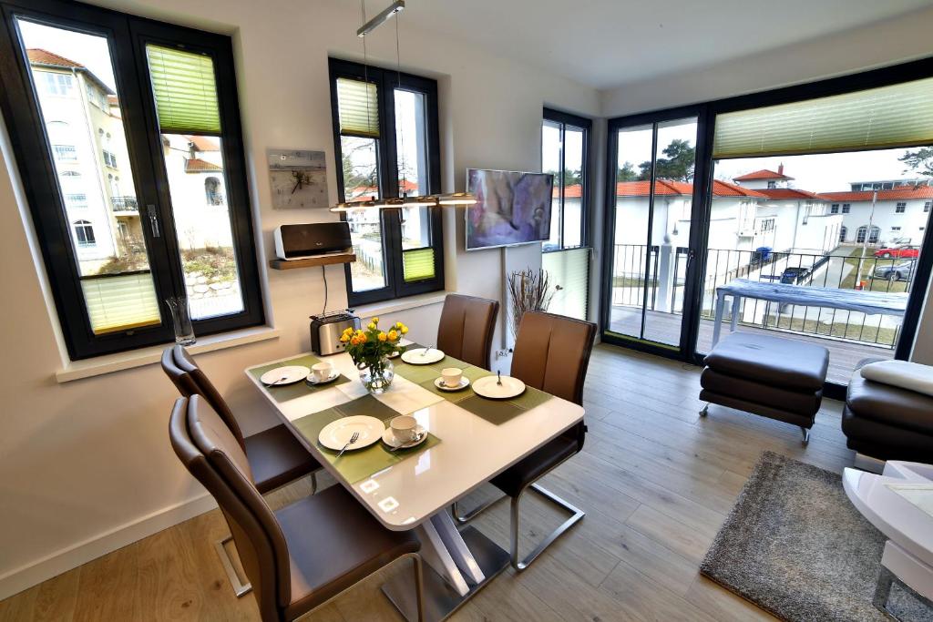 uma sala de jantar com mesa, cadeiras e janelas em Ferienwohnung "Lachmöwe" Baabe em Baabe