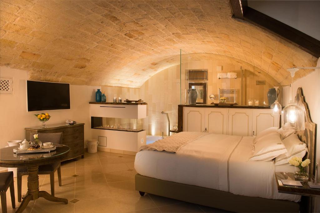 a bedroom with a large white bed and a table at Hotel Don Ferrante in Monopoli