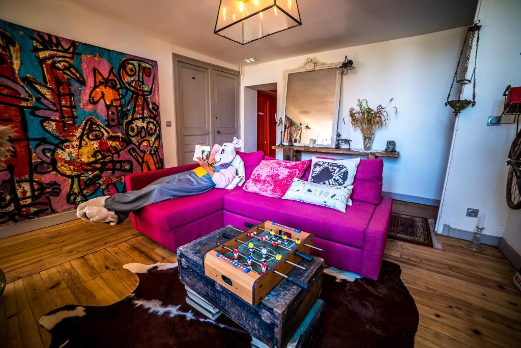 a person laying on a purple couch in a living room at Les chambres de Lily in Carresse