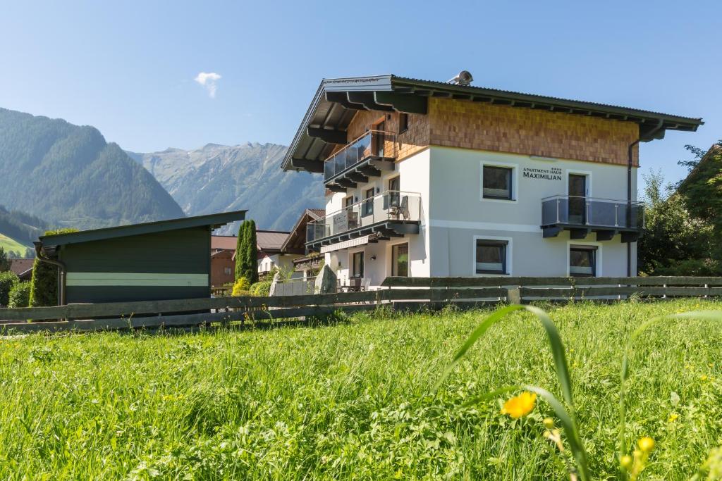 um edifício com um campo relvado à sua frente em Apartmenthaus Maximilian em Neukirchen am Grossvenediger