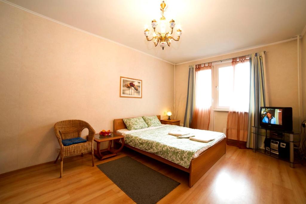 モスクワにあるApartment on ulitsa Ostrovityanovaのベッドルーム(ベッド1台、テレビ、シャンデリア付)