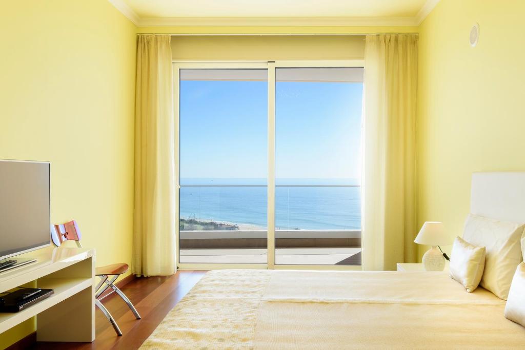 sypialnia z dużym oknem z widokiem na ocean w obiekcie Porto de Mos Golf & Beach B&B AL-40312 w Lagosie