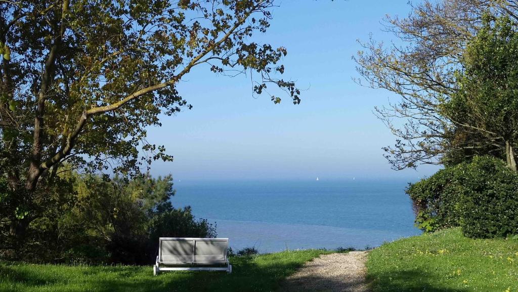 a bench sitting on a hill next to the ocean at Les Graves in Villerville