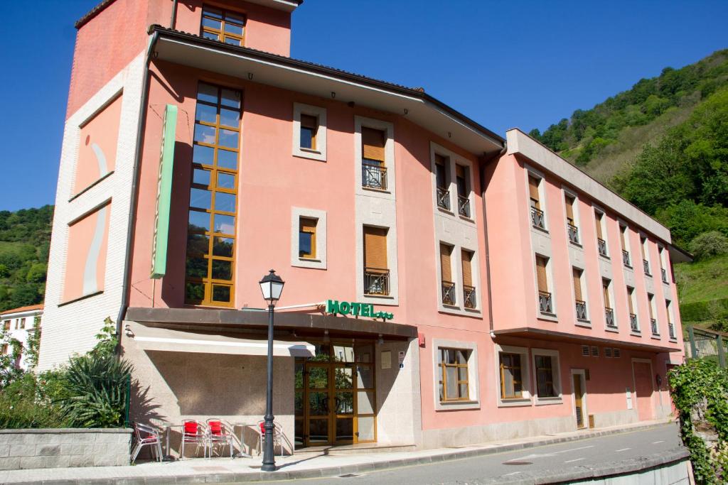 ein rosafarbenes Gebäude an der Straßenseite in der Unterkunft Hotel las Cruces in Belmonte de Miranda