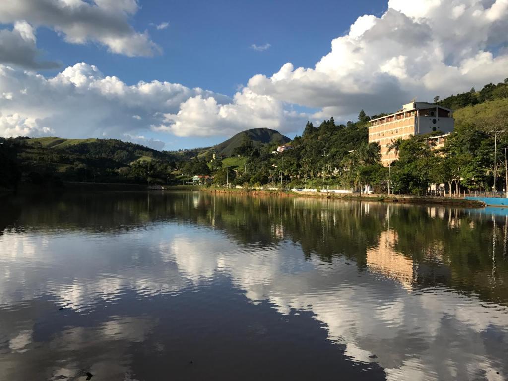 a body of water with buildings and trees and clouds at Cavalinho Branco Apartamento in Águas de Lindoia