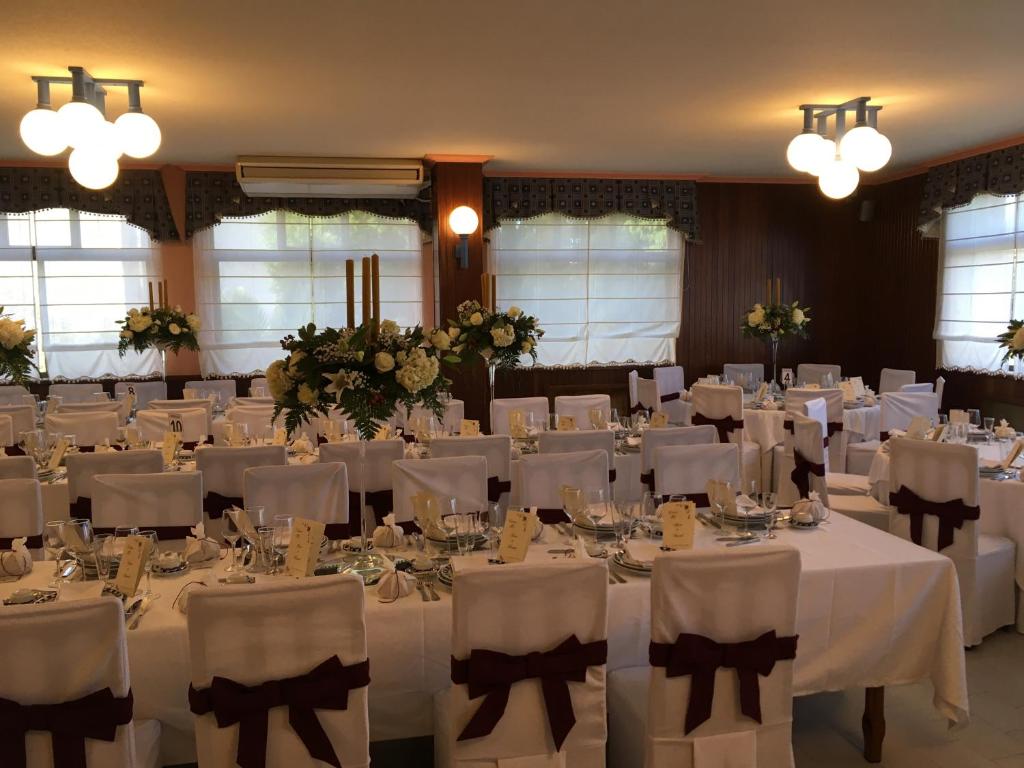 un salón de banquetes con mesas y sillas blancas en Hotel O Castelo, en Cervo