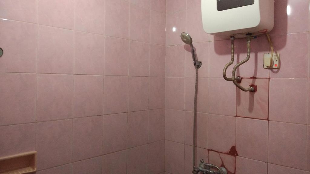 a pink bathroom with a shower with a phone on the wall at Puri Bebengan Bungalows in Ubud