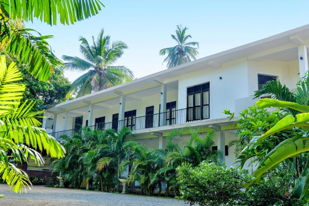 een gebouw met palmbomen ervoor bij Hotel Ancient Village in Polonnaruwa