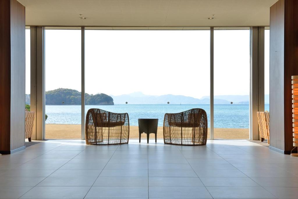 um quarto com cadeiras e vista para o oceano em Shodoshima International Hotel em Tonosho