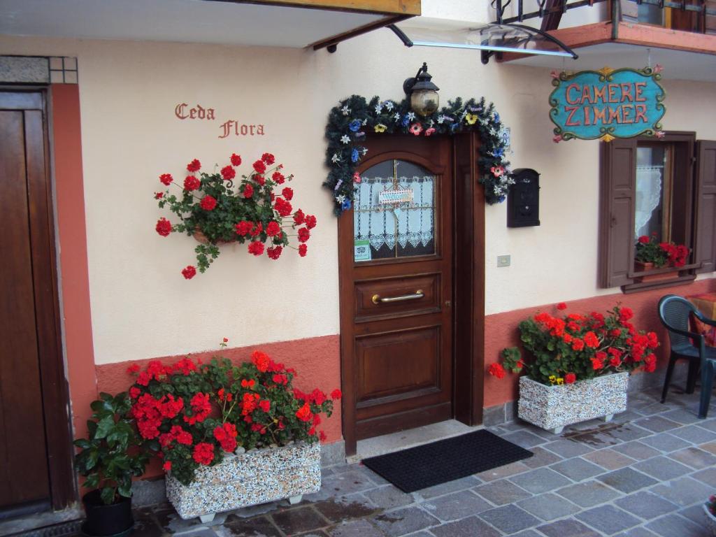 a door to a restaurant with red flowers and plants at La casa di Beppe appartamento in Danta