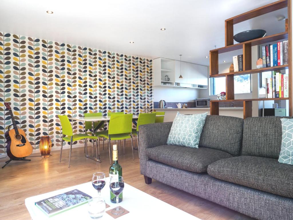 a living room with a couch and a table with green chairs at qTownPad in Queenstown