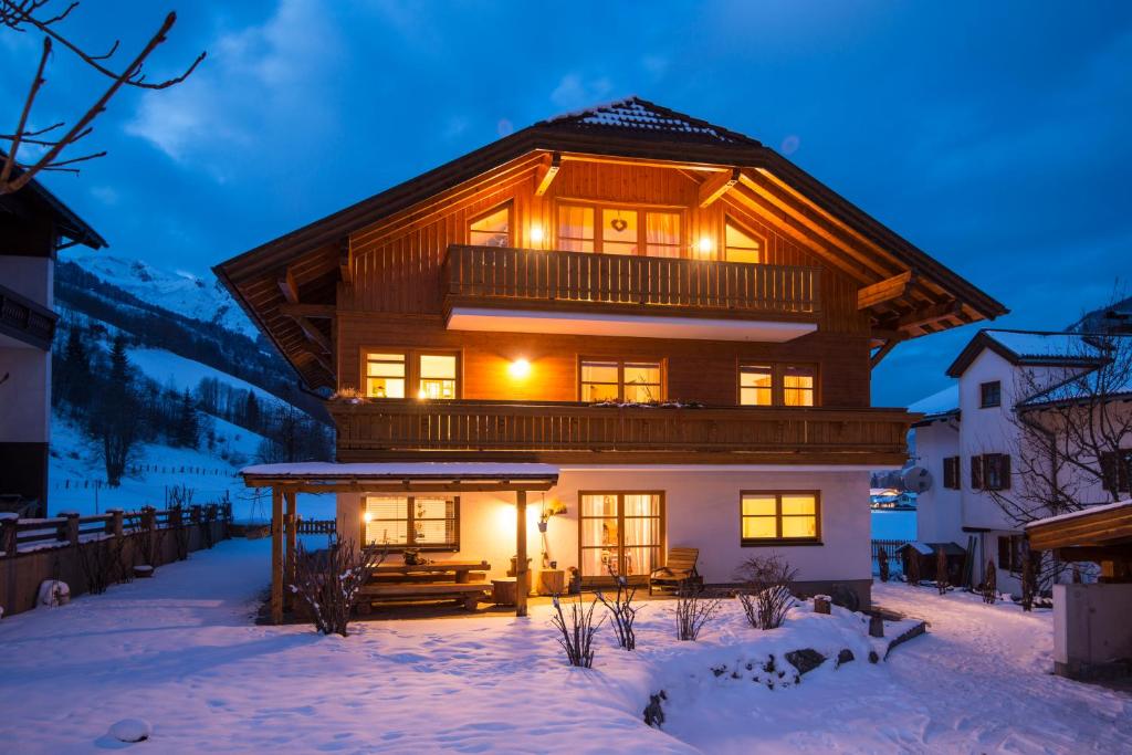 une maison en rondins dans la neige la nuit dans l'établissement Landhaus Resinger, à Bad Hofgastein