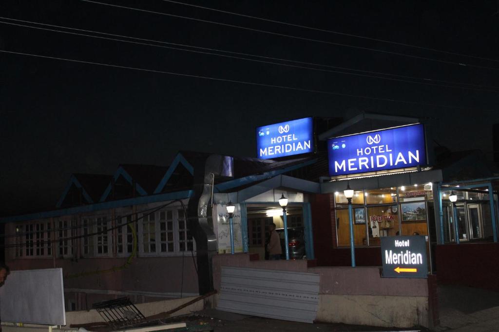 a gas station at night with blue signs on it at Hotel Meridian With Car Parking in Shimla