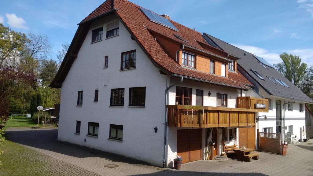 un grand bâtiment blanc avec un toit en gambrel dans l'établissement Gästehaus zur Mühle Dehm, à Friedrichshafen