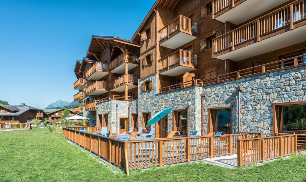een resortgebouw met balkons en een tuin bij CGH Résidences & Spas Les Chalets De Laÿssia in Samoëns