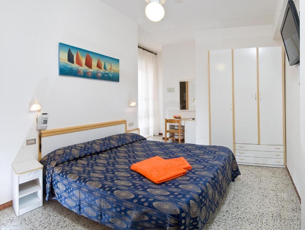 a bedroom with a bed with an orange pillow on it at Hotel Venus in Riccione