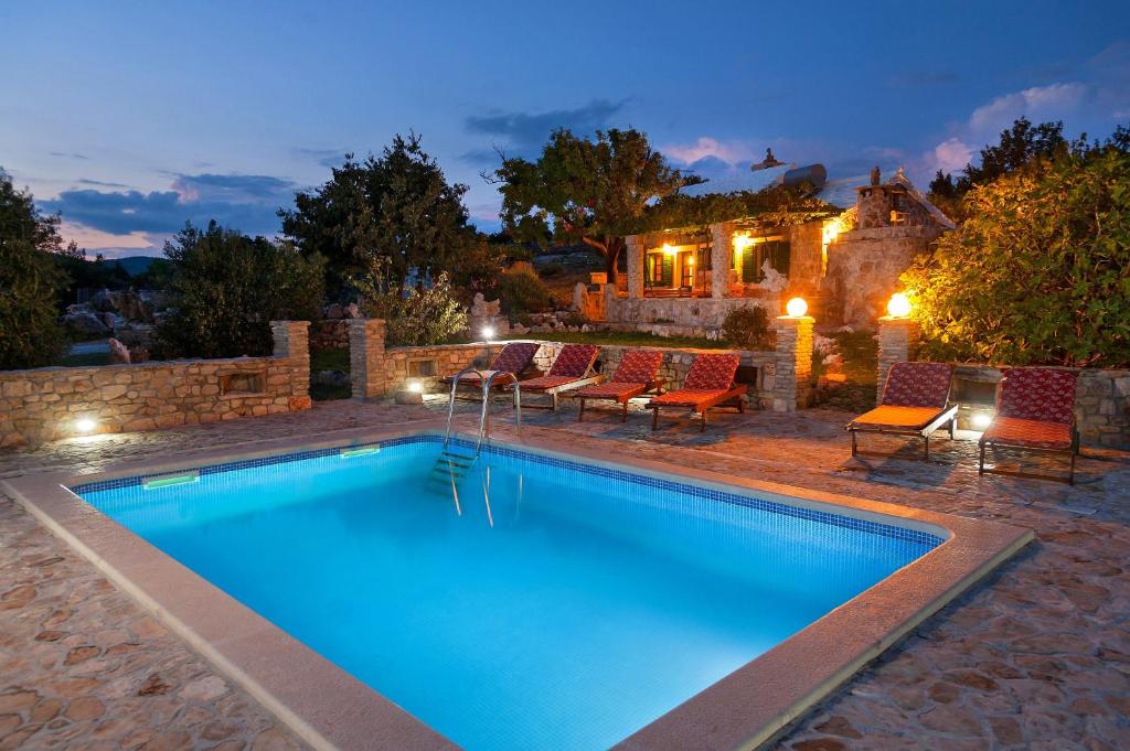 a pool with chairs and a house in the background at The Ultimate Escape - two traditional cottages & private pool in Selca