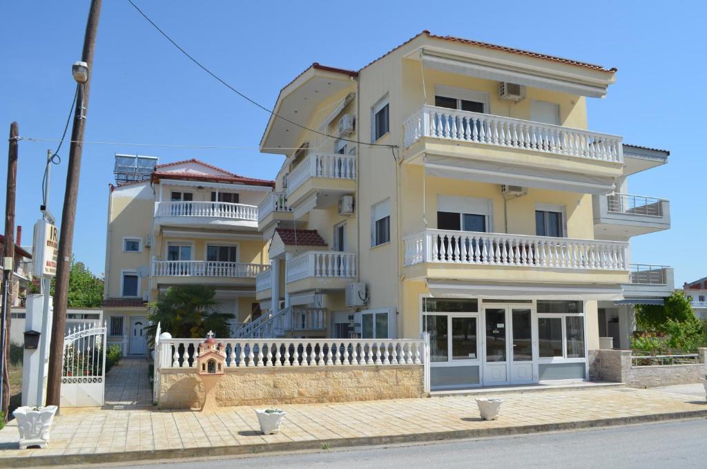 a woman standing in front of a yellow building at Irini Apartments in Keramotí