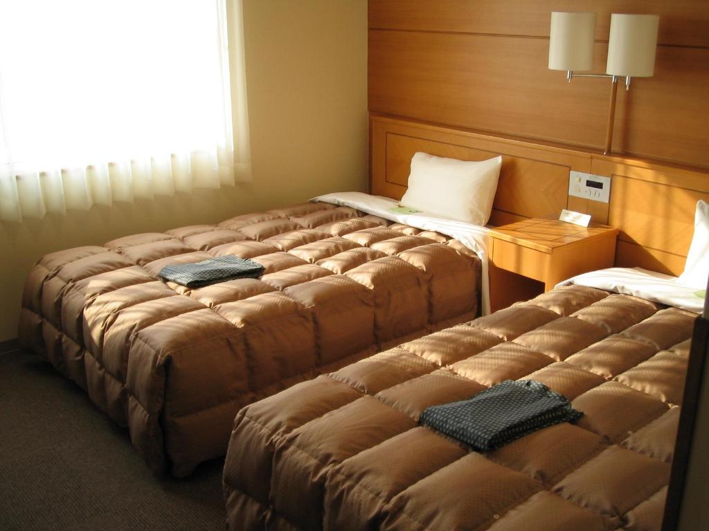 two large beds in a hotel room with at Hotel Route-Inn Yukuhashi in Yukuhashi