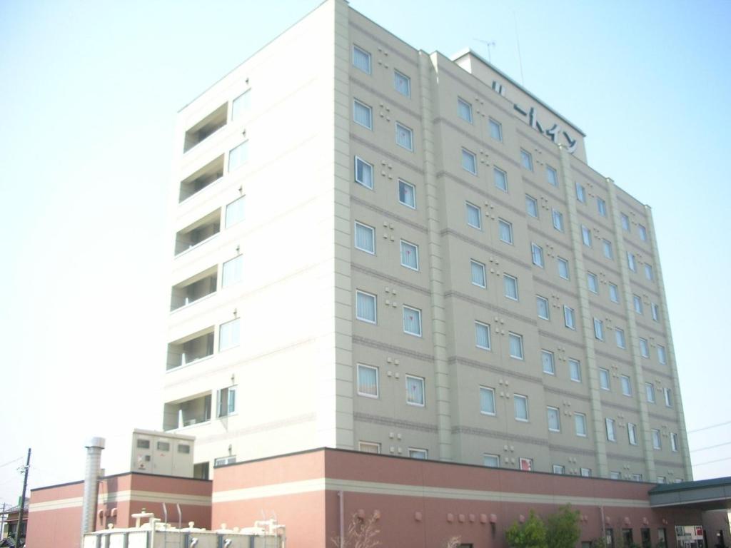 a tall white building on top of a building at Hotel Route-Inn Kikugawa Inter in Kikugawa